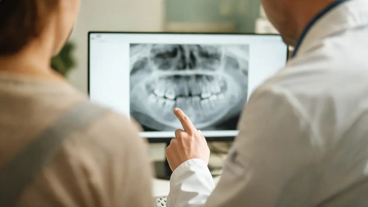 A patient and a clinician reviewing a dental panoramic X-ray together on a monitor
